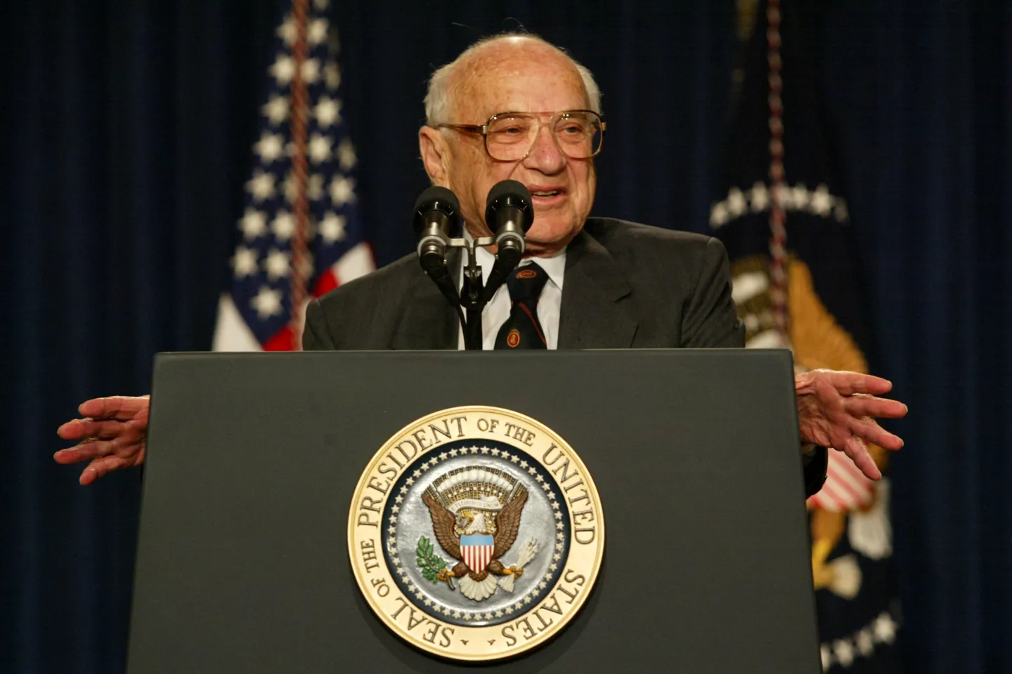 milton friedman speaking at a podium